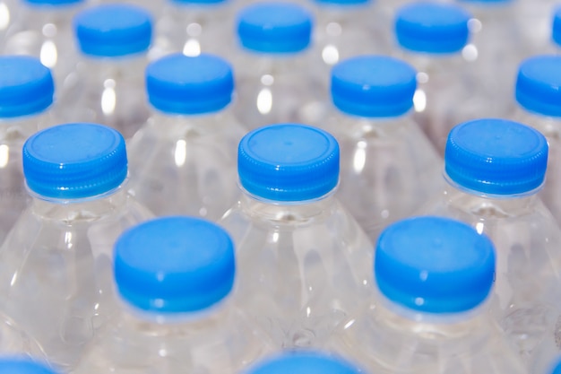 Fila de botellas de agua. Botellas con tapones azules para agua potable.