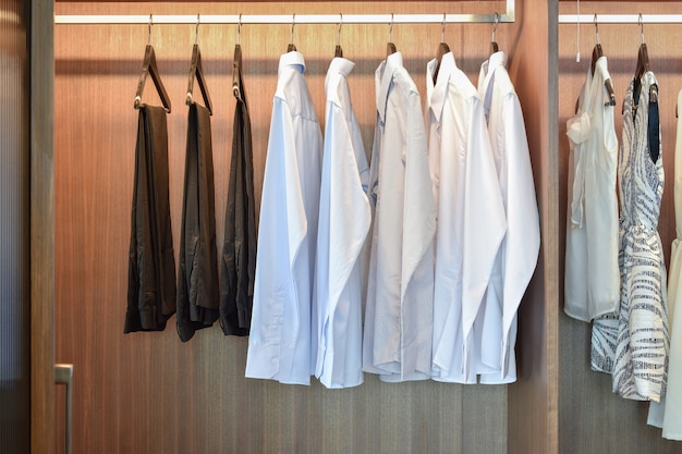Fila de camisas blancas colgando en el armario de madera