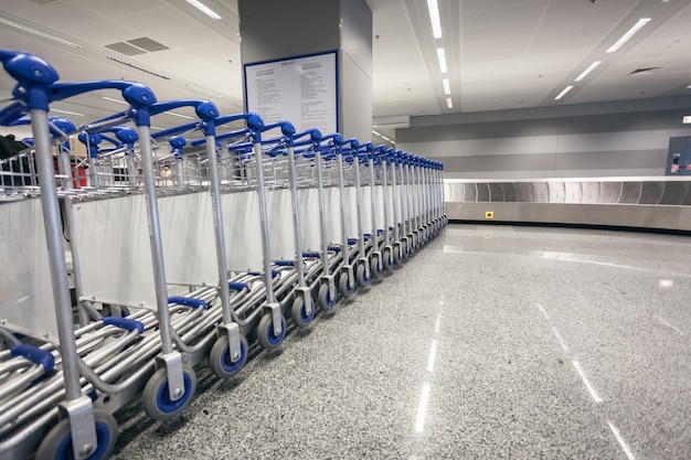 Fila de carros de equipaje en la terminal de llegadas del aeropuerto