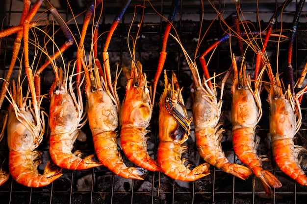 Fila de coloridas gambas a la parrilla sobre fuego caliente.