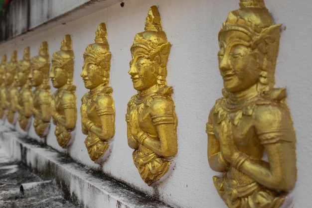 Fila de baixos-relevos dourados de Buda na parede do templo budista Samui Tailândia de Wat Kiri Wongkaram