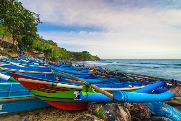 fila de barcos de pesca azuis na praia de Menganti, no centro de Java, Indonésia