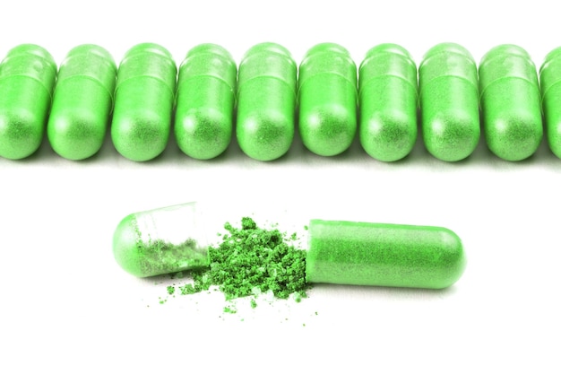 Fila de cápsulas orgânicas de cor verde ufo isoladas em fundo branco fechado com uma aberta