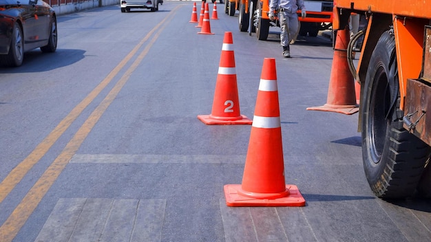 Fila de cones de trânsito com seção baixa de caminhões-guindaste estacionados na estrada de asfalto