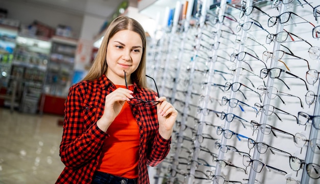 Fila de óculos em uma loja de óticas Óculos Stand com óculos na loja de ótica Mulher escolhe óculos Correção da visão