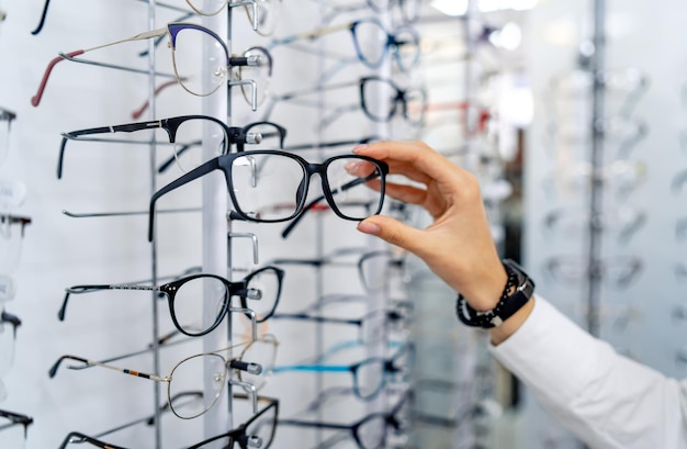 Fila de óculos em uma loja de óticas óculos stand com óculos na loja de ótica mulher escolhe óculos correção da visão