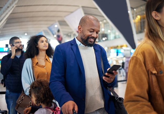 Fila de viagem e telefone com homem negro no aeroporto para férias de voo e imigração Comunicação feliz e tecnologia com empresário alinhado com bagagem para viagem de férias e primeira classe