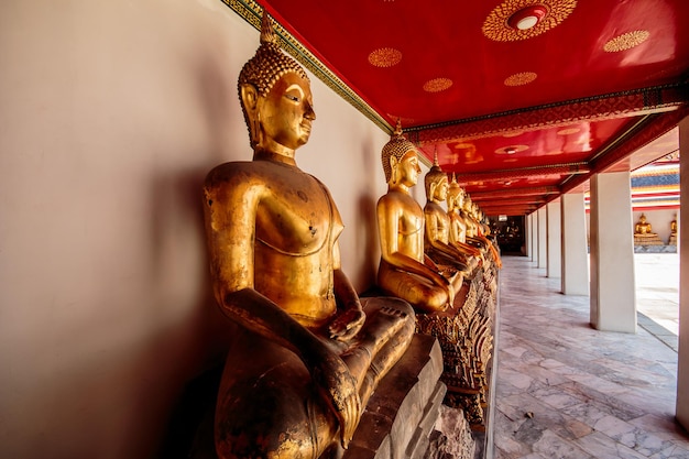 Fila de estatuas de Buda de oro en posición de loto en el templo Wat Pho Bangkok Thailand