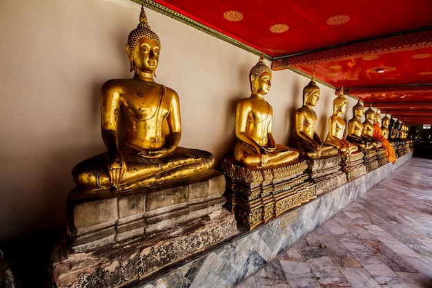 Fila de estatuas de Buda de oro en posición de loto en el templo Wat Pho Bangkok Thailand