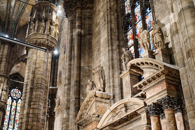 Fila de estatuas en el interior de columnas bajo las vidrieras de la catedral de milán, italia