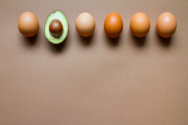 Fila de huevos de gallina y medio aguacate crudo