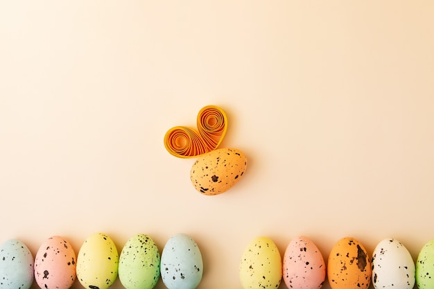 Fila de huevos multicolores sobre fondo pastel Huevo divertido como un abejorro con alas Concepto de Pascua