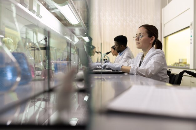 Fila de jóvenes científicos interculturales que trabajan en un gran laboratorio químico