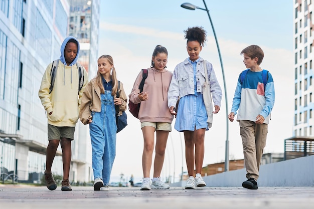 Fila de jóvenes multiculturales en ropa informal caminando por la calle