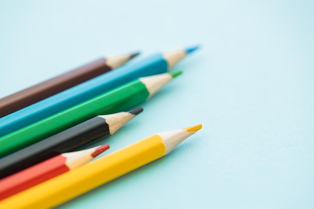 Fila de lápices de colores con onda sobre fondo azul.