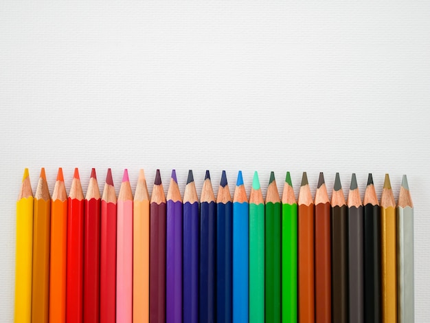 fila de lápices de colores transparente sobre fondo de papel de pintura blanca