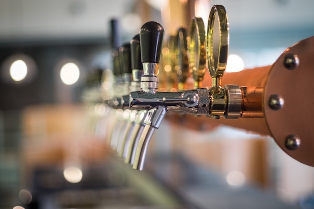 Fila de la lengüeta de la cerveza de barril en la cima de la barra contraria en la opinión del primer, época de la celebración.