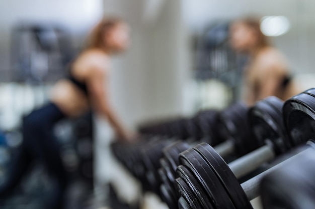 Fila de mancuernas cerca del espejo en el fondo del gimnasio deportivo con un concepto femenino de Closeup Sports y un estilo de vida saludable