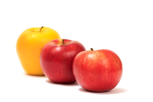 Fila de manzanas rojas y amarillas maduras sobre un fondo blanco aislado.