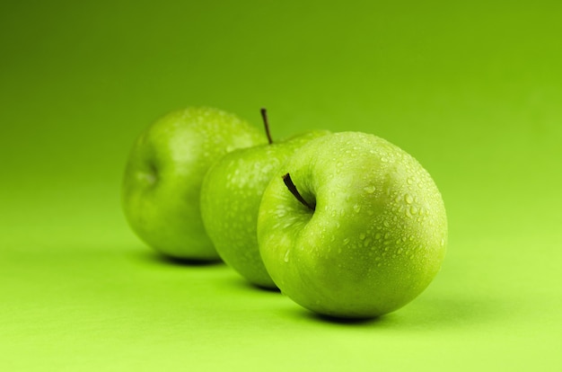 Fila de manzanas verdes sobre fondo verde