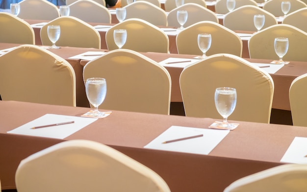 Fila de mesa y silla con vidrio de agua fría en la sala de reuniones del seminario.