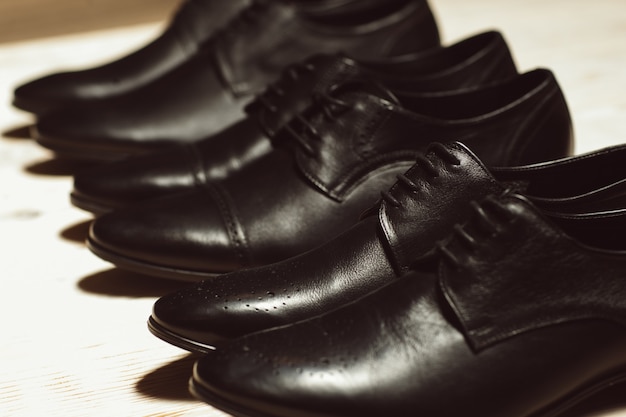 Fila de nuevos zapatos clásicos masculinos sobre un piso de madera