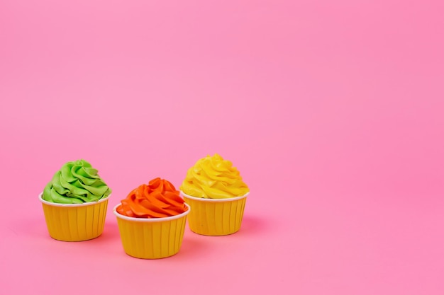 Una fila de pastelitos de colores sobre un fondo rosa