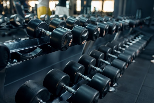 Fila de pesas en primer plano de gimnasio. Equipo para ejercicios de fitness, peso pesado para entrenamiento deportivo.