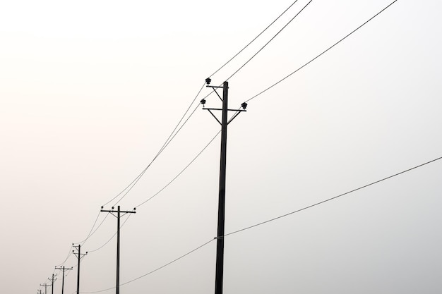 Una fila de postes de transmisión de electricidad bajo el cielo nublado con espacio de copia