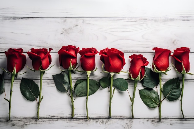 Una fila de rosas rojas sobre una mesa de madera blanca.