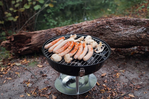 Fila de salchichas de cerdo y ternera a la parrilla sobre un fuego de barbacoa en las vacaciones de verano