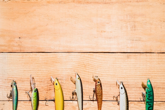 Foto fila de señuelos de pesca de colores en el escritorio de madera