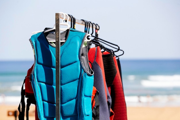 Una fila de trajes de neopreno colgando de un estante en una escuela de surf