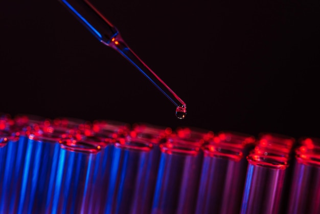 Fila de tubos de ensayo Concepto de gota líquida de laboratorio médico o científico con cuentagotas en fondo de tono azul de cerca imagen de micro fotografía