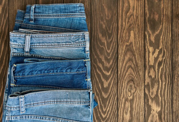 Fila vertical de jeans diferentes de moda sobre un fondo de madera con espacio de copia