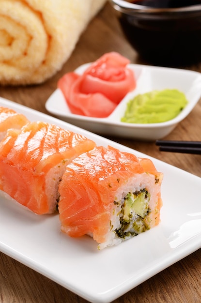 Filadélfia rolo sushi em um prato branco com molho de soja wasabi e gengibre