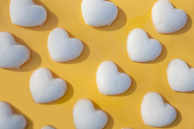 Filas de bolas de nieve en forma de corazón sobre fondo amarillo