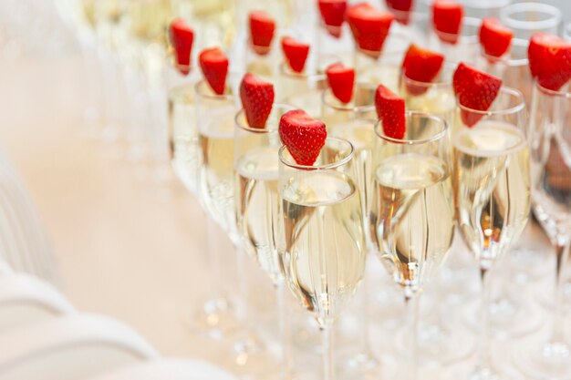 Filas de copas de champán decoradas con fresas en la mesa del buffet. De cerca.