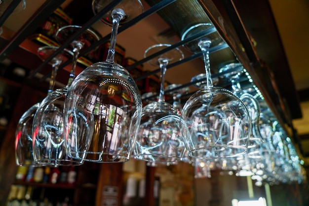 Filas de copas de vino limpias cuelgan sobre el bar en el café Primer plano