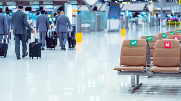 Filas de cadeiras castanhas vazias com o sinal de adesivo de posição sentada para distanciamento social no aeroporto