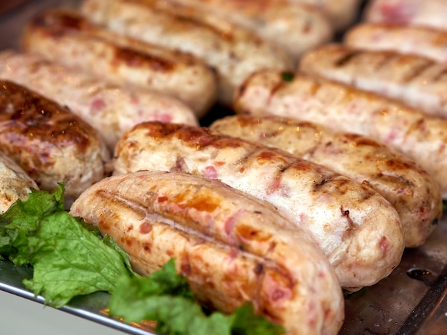 Foto filas de salchichas de carne de pollo recién asadas en bandeja con lechuga fresca