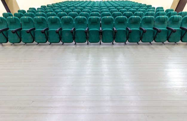 Filas de sillas verdes en el auditorio de un cine o teatro rural.