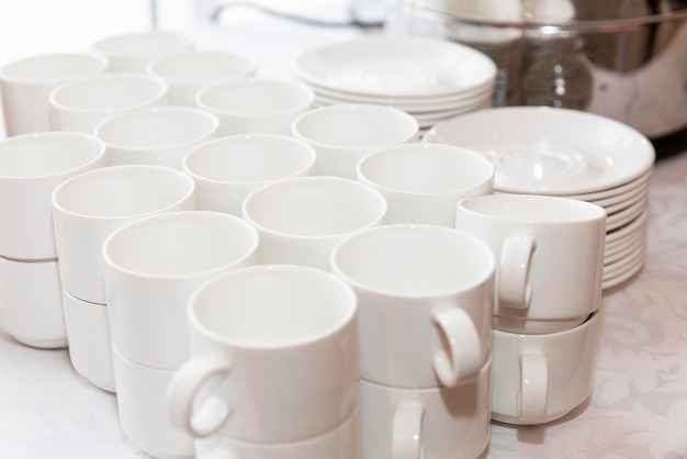 Filas de tazas blancas vacías en la mesa del buffet. Reuniones de empresa y celebraciones. De cerca.