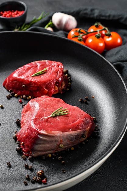 Filé cru bife de mignon em uma frigideira. lombinho de carne. parede preta. vista do topo