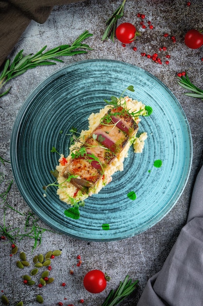 Filé de atum frito com cuscuz e ervas numa mesa de pedra cinzentaxa