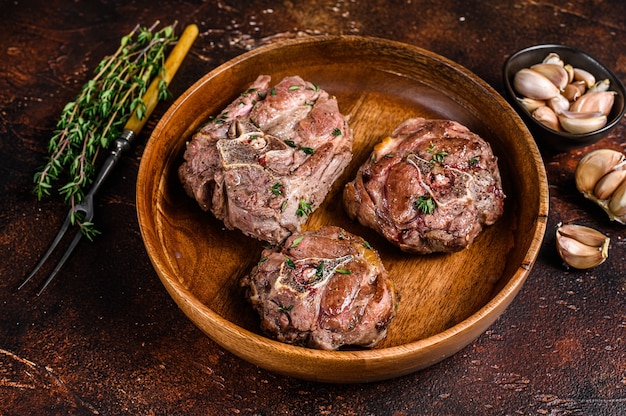 Filé de carne de pescoço de cordeiro frito em prato de madeira com ervas