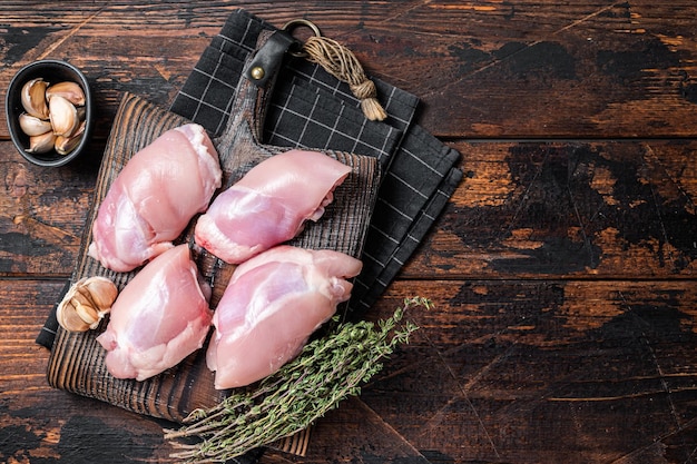 Filé de coxa de frango Carne crua desossada e sem pele em uma tábua de corte Fundo de madeira Vista superior Copiar espaço