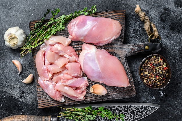 Filé de coxa de frango cru fatiado em uma tábua de madeira.