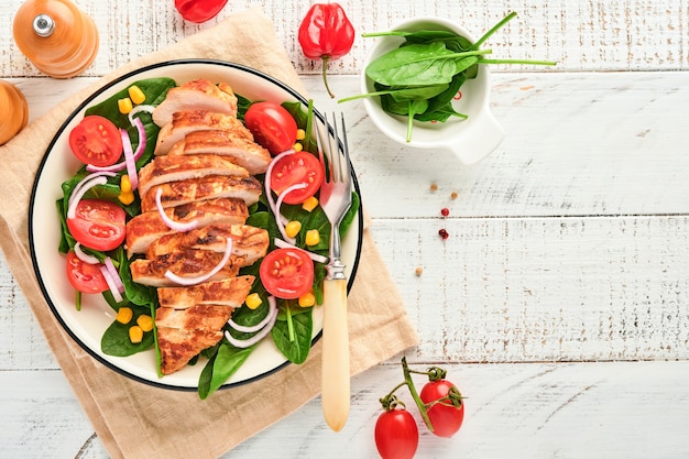 Filé de frango com salada de espinafre, tomate cereja, centáurea e cebola. Comida saudável. Dieta ceto, conceito de almoço de dieta. Vista superior em fundo branco.