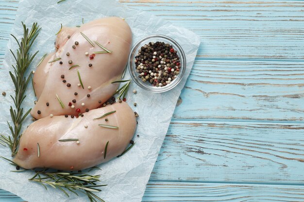 Filé de frango cru com alecrim e especiarias em um fundo azul de madeira